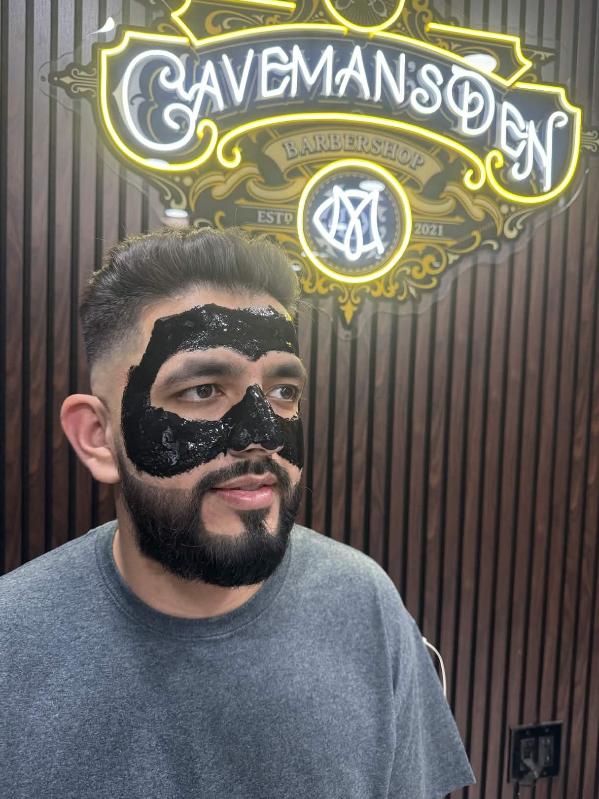 Facial treatment with charcoal mask at Caveman's Den Barbershop Astoria