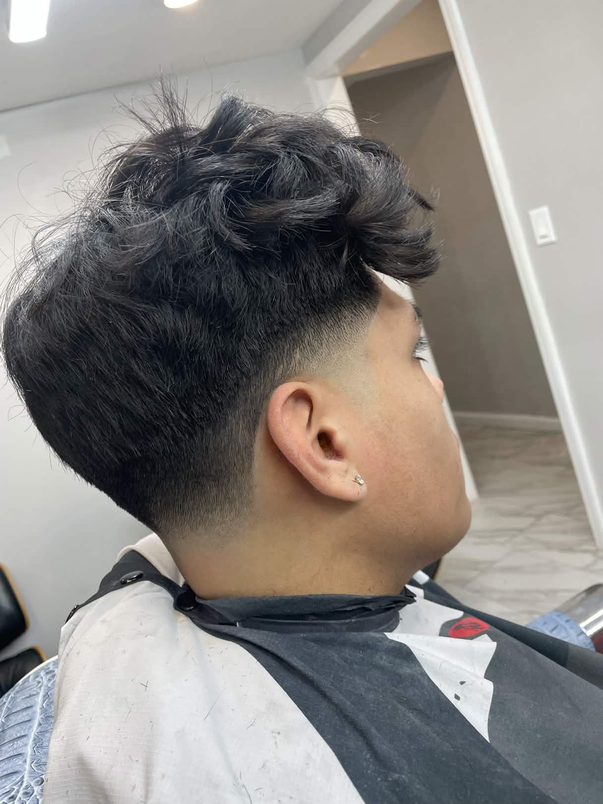Textured mullet fade — back and side view at Caveman's Den