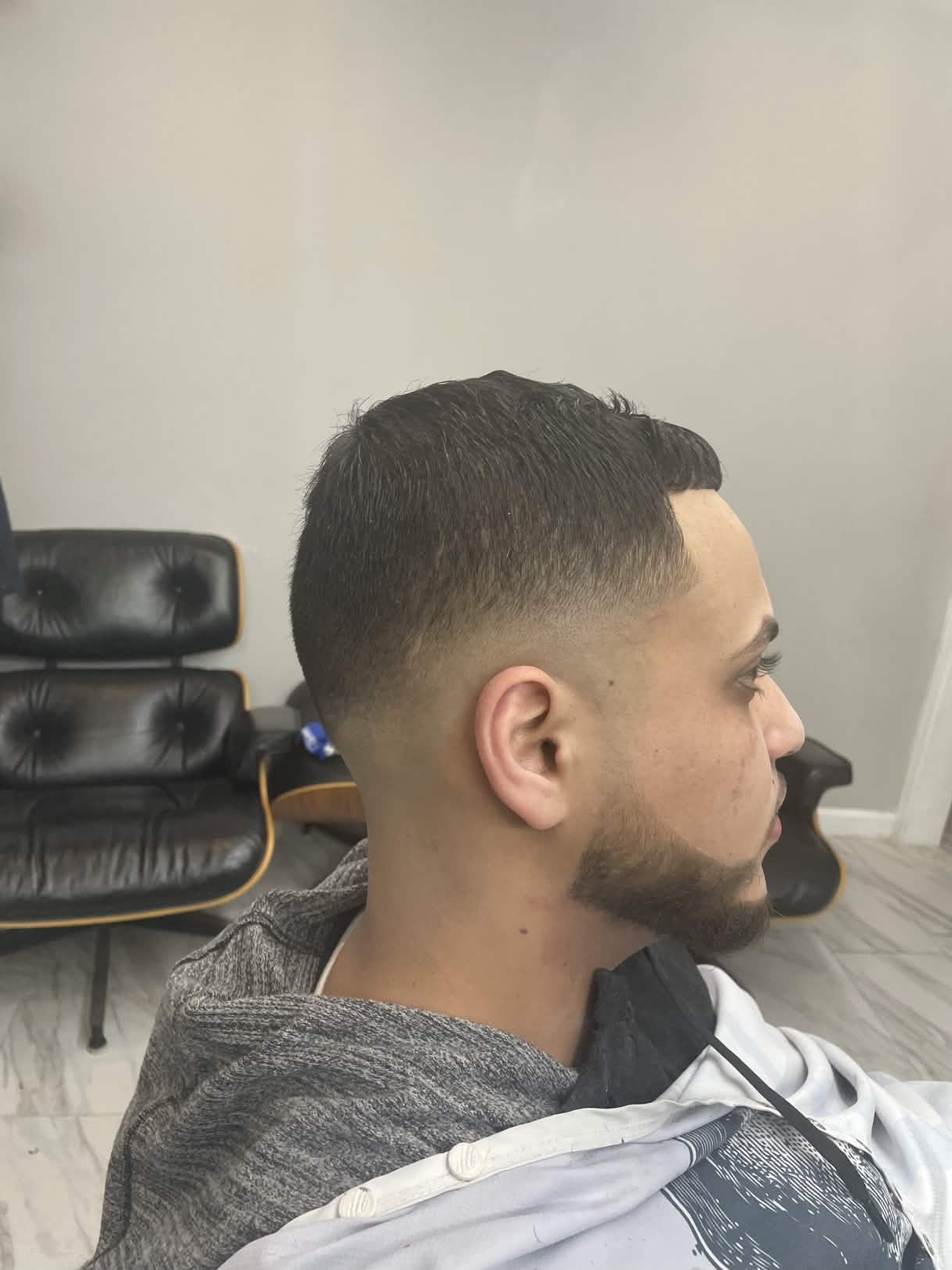 Classic taper fade with beard at Caveman's Den — shop lounge visible