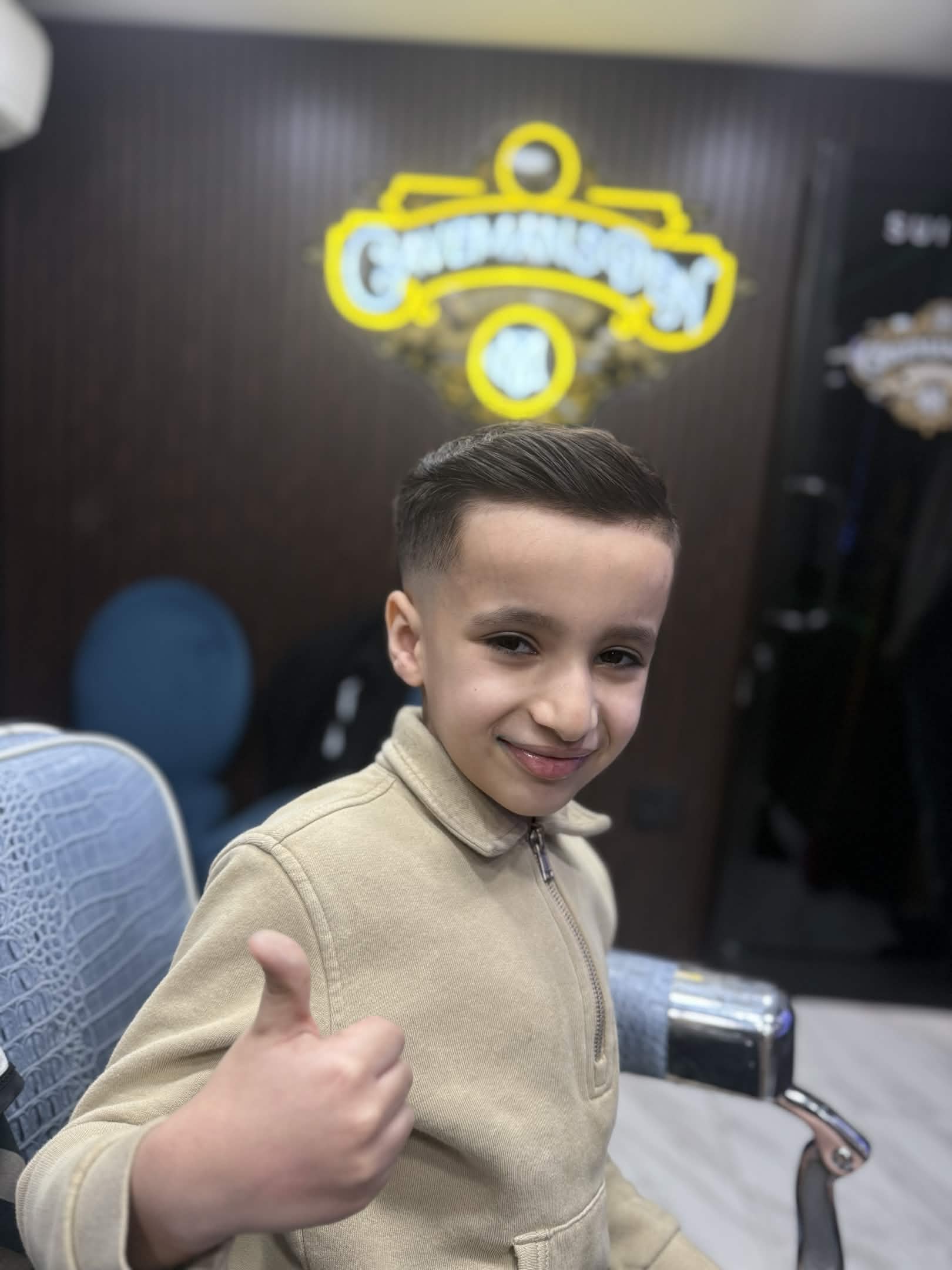 Kids side part fade at Caveman's Den — smiling boy thumbs up