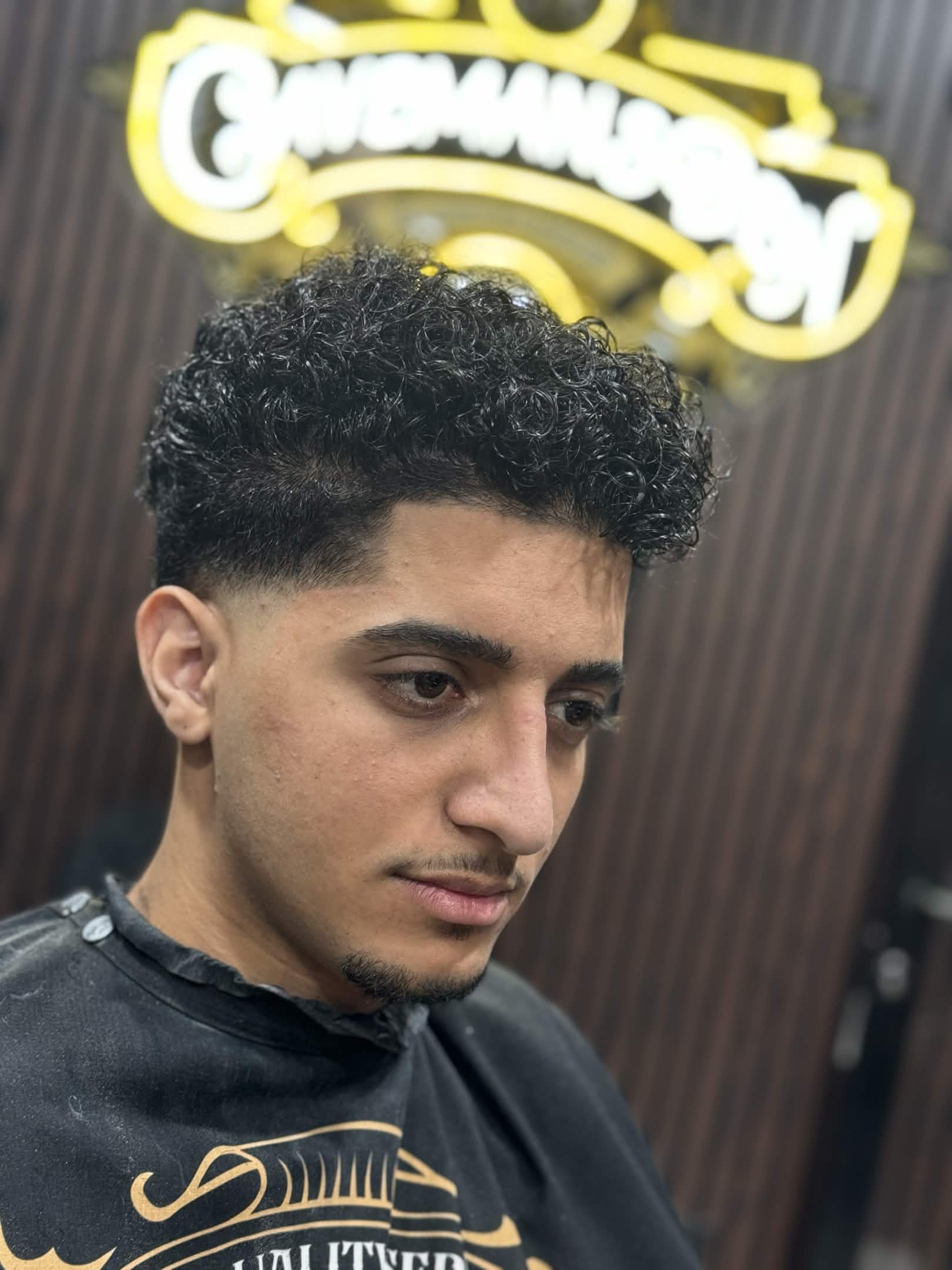 Curly top with low fade at Caveman's Den Barbershop Astoria