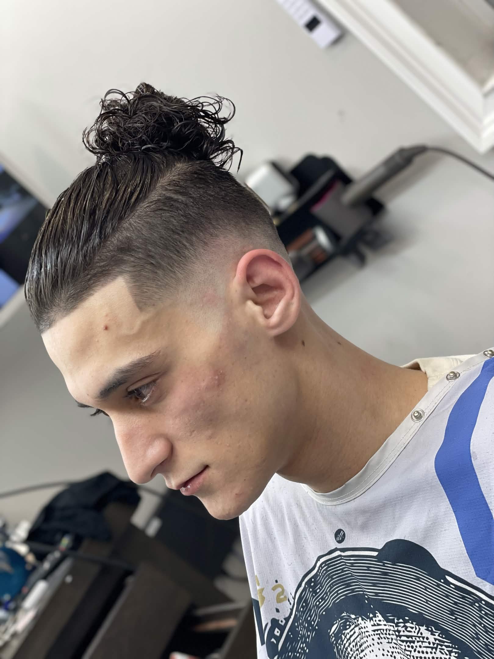 Curly bun with skin fade side profile — Caveman's Den Astoria NY
